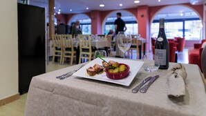 Una mesa de comedor con un plato de comida, vino y cubiertos.