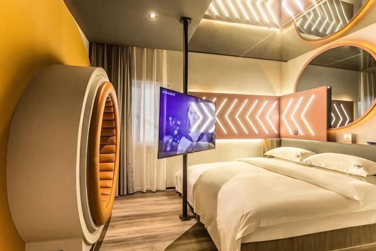 Una camera d'albergo moderna con un grande letto, una televisione e un originale design a parete circolare.