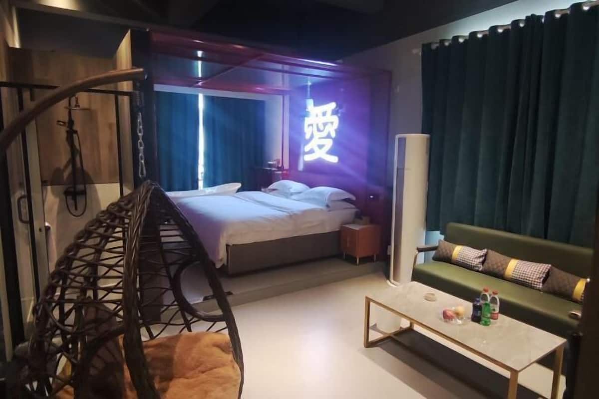 Una camera d'albergo moderna con un letto, una poltrona sospesa, un divano e un comodino con articoli da toilette.
