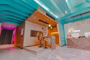 A reception area with a wooden reception desk, a digital screen, and a ceiling with a unique wave-like design. - QIngGuo intelligence Hotel (Jiashan)