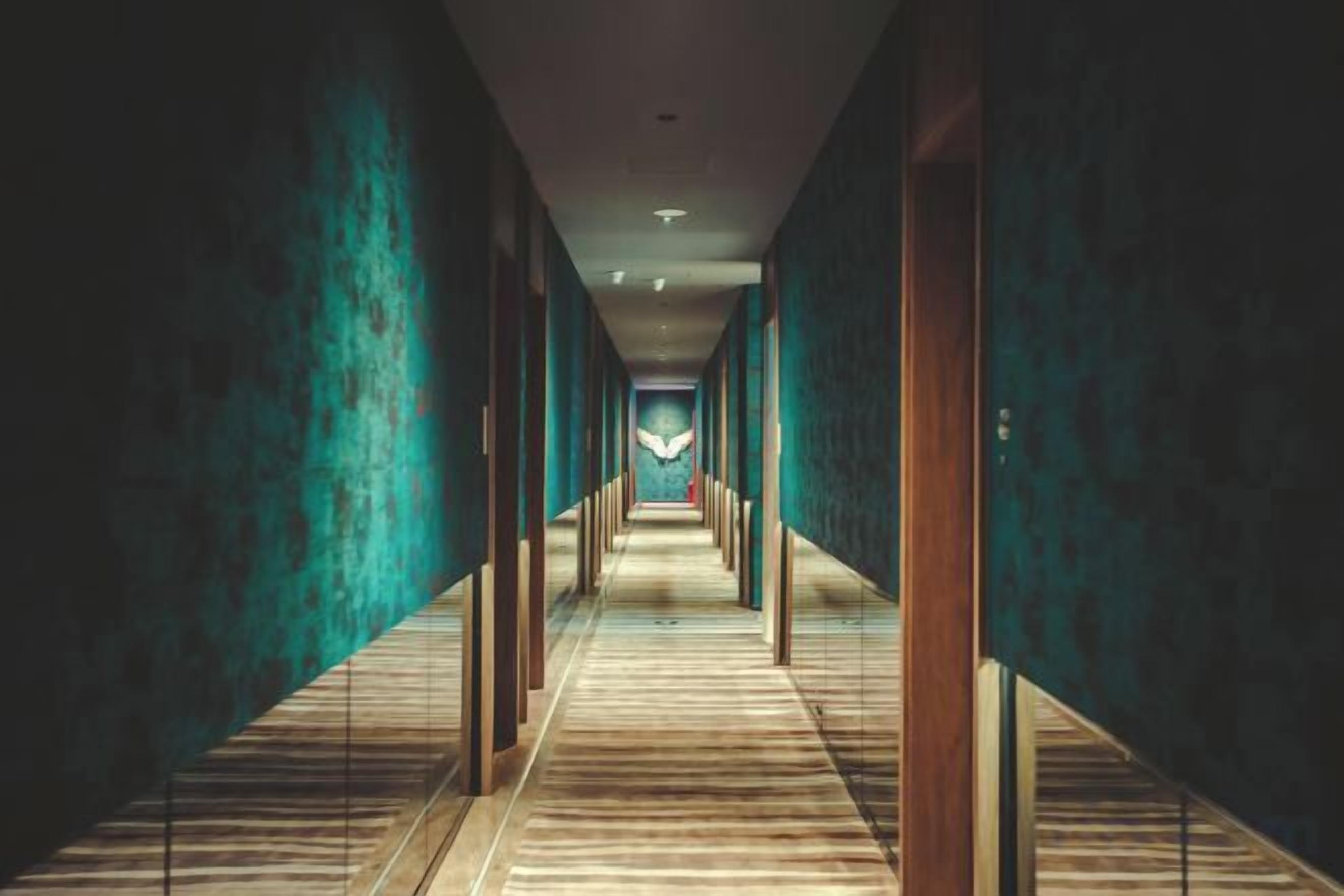 A long, narrow hallway with a wooden floor and teal walls.