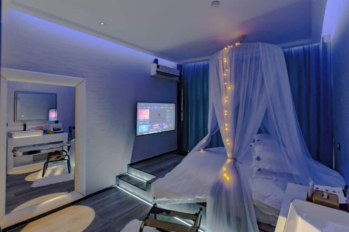 Una camera d'albergo moderna con un letto, una TV e una scrivania con un computer.