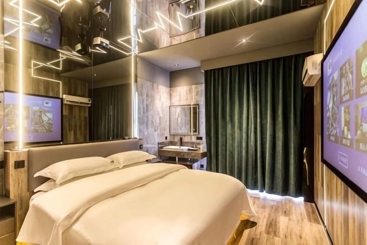 Una camera d'albergo moderna con un letto grande, una toeletta con specchio e uno schermo televisivo.