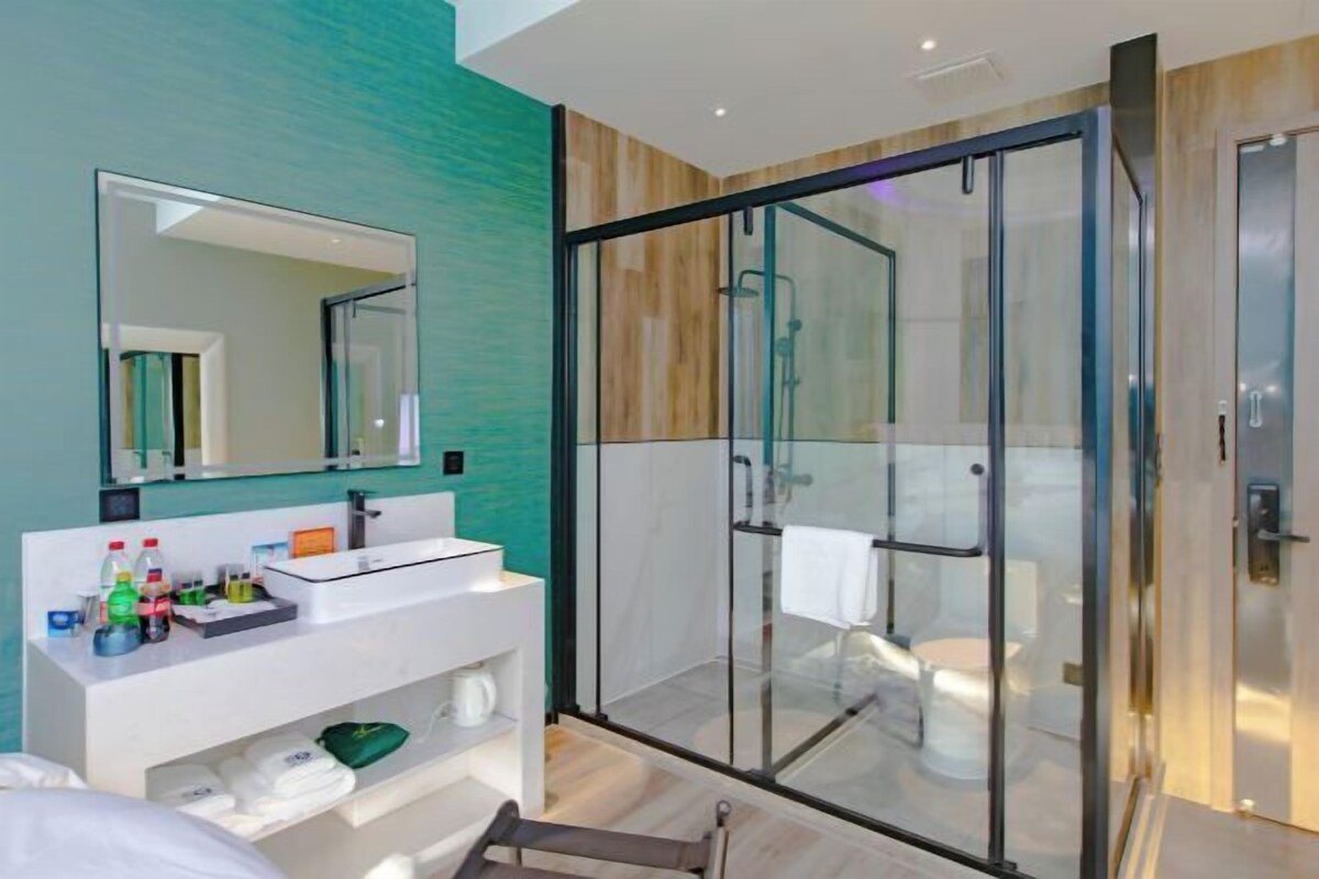 A modern bathroom with a glass-enclosed shower, a white vanity, and a large mirror.