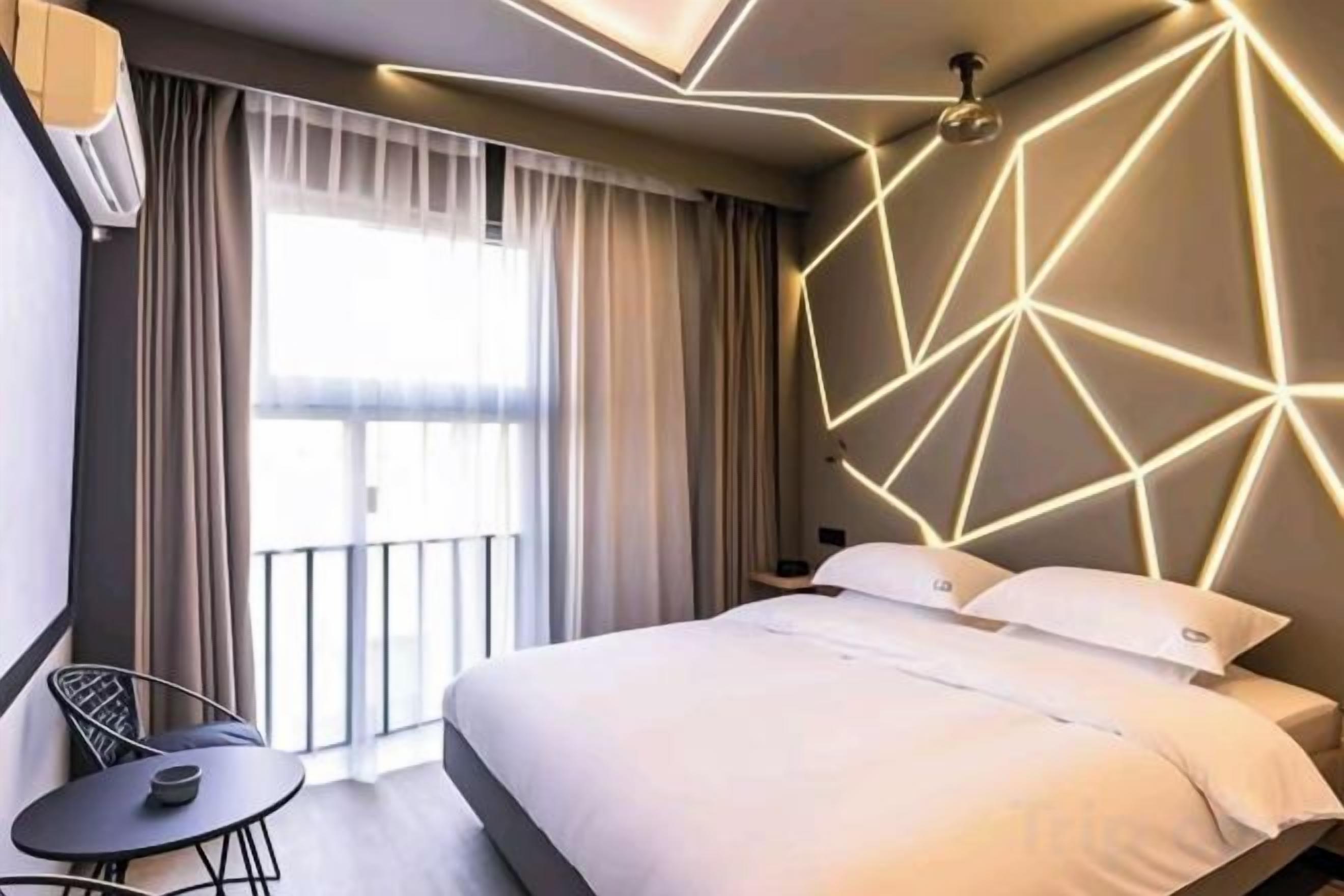Habitació d'hotel moderna amb llit, taula petita i vistes a l'exterior per una finestra.