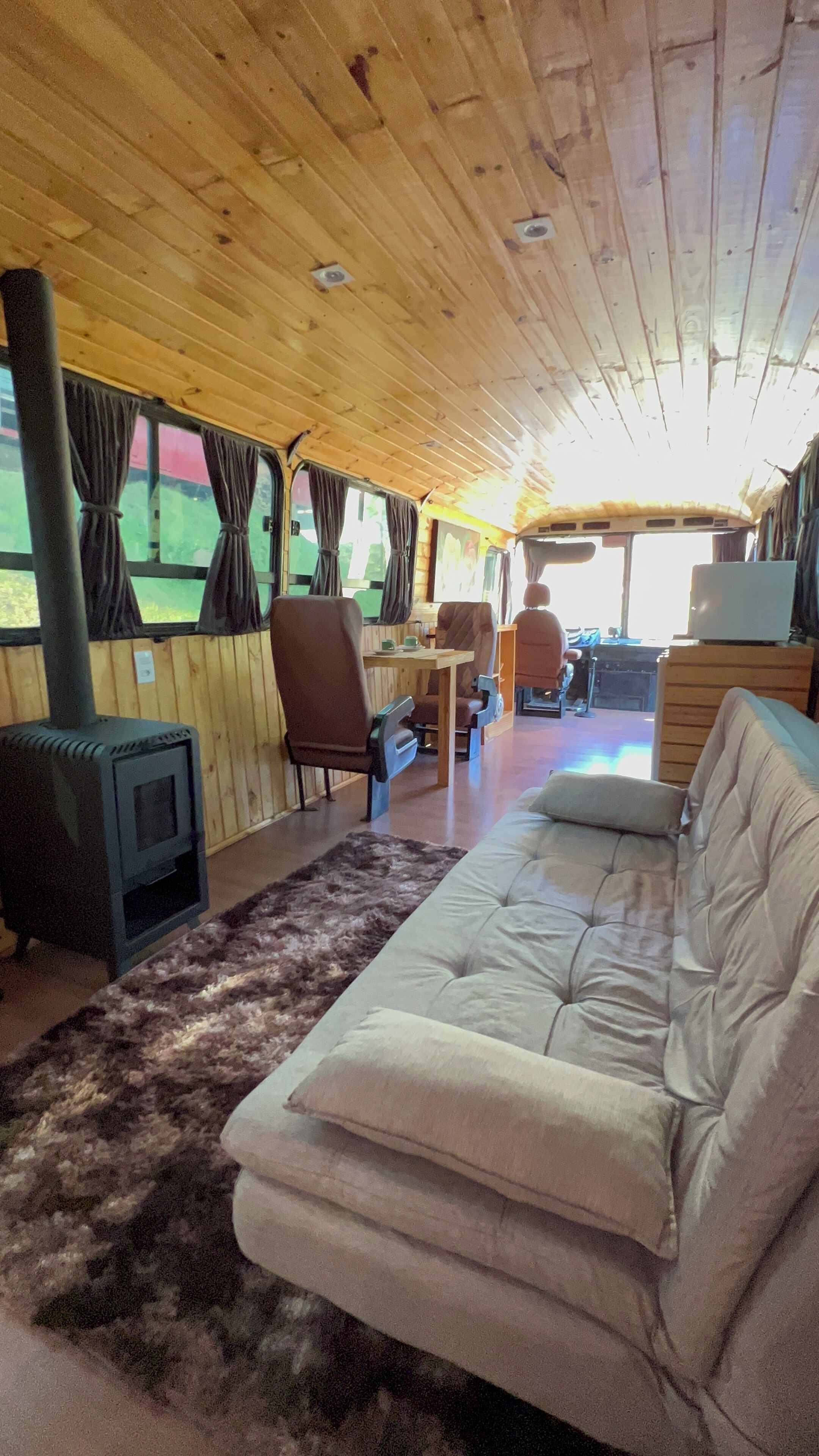 Ein gemütliches Blockhaus-Interieur mit einer Couch, Sesseln, einem Tisch, einem Kamin und Vorhängen.