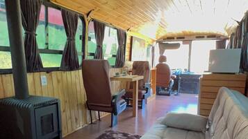 Ein gemütliches Blockhaus-Interieur mit einer Couch, Sesseln, einem Tisch, einem Kamin und Vorhängen.