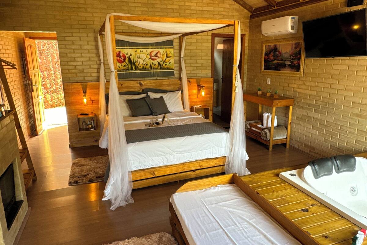 A spacious bedroom with a large bed, a separate sofa bed, a fireplace, and a television.
