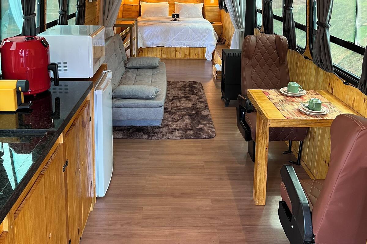 A cozy interior with a bed, sofa, dining table, and kitchen area.