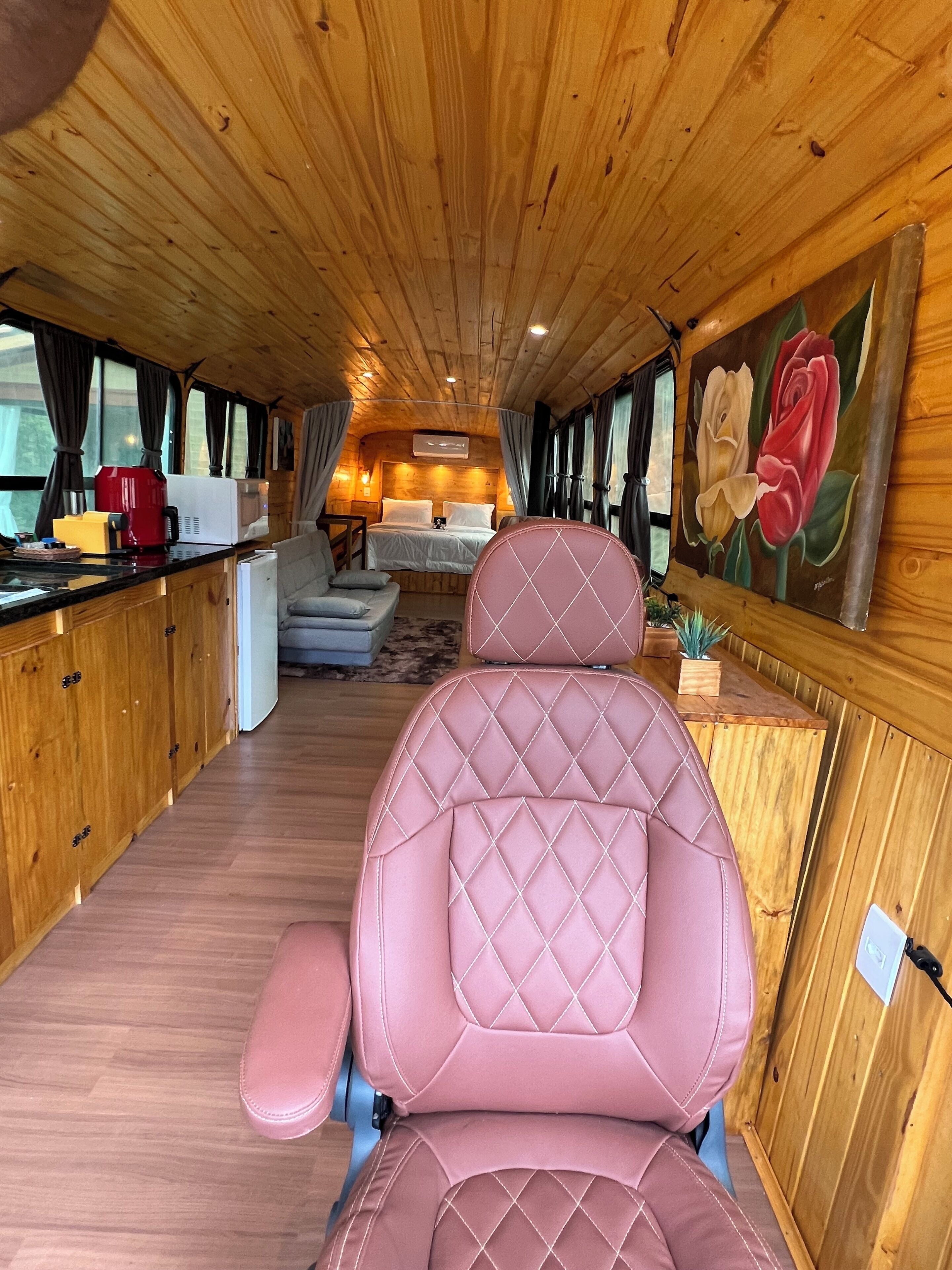 Un interior acogedor con paredes de madera, una cama, una zona de estar y un cuadro de rosas.