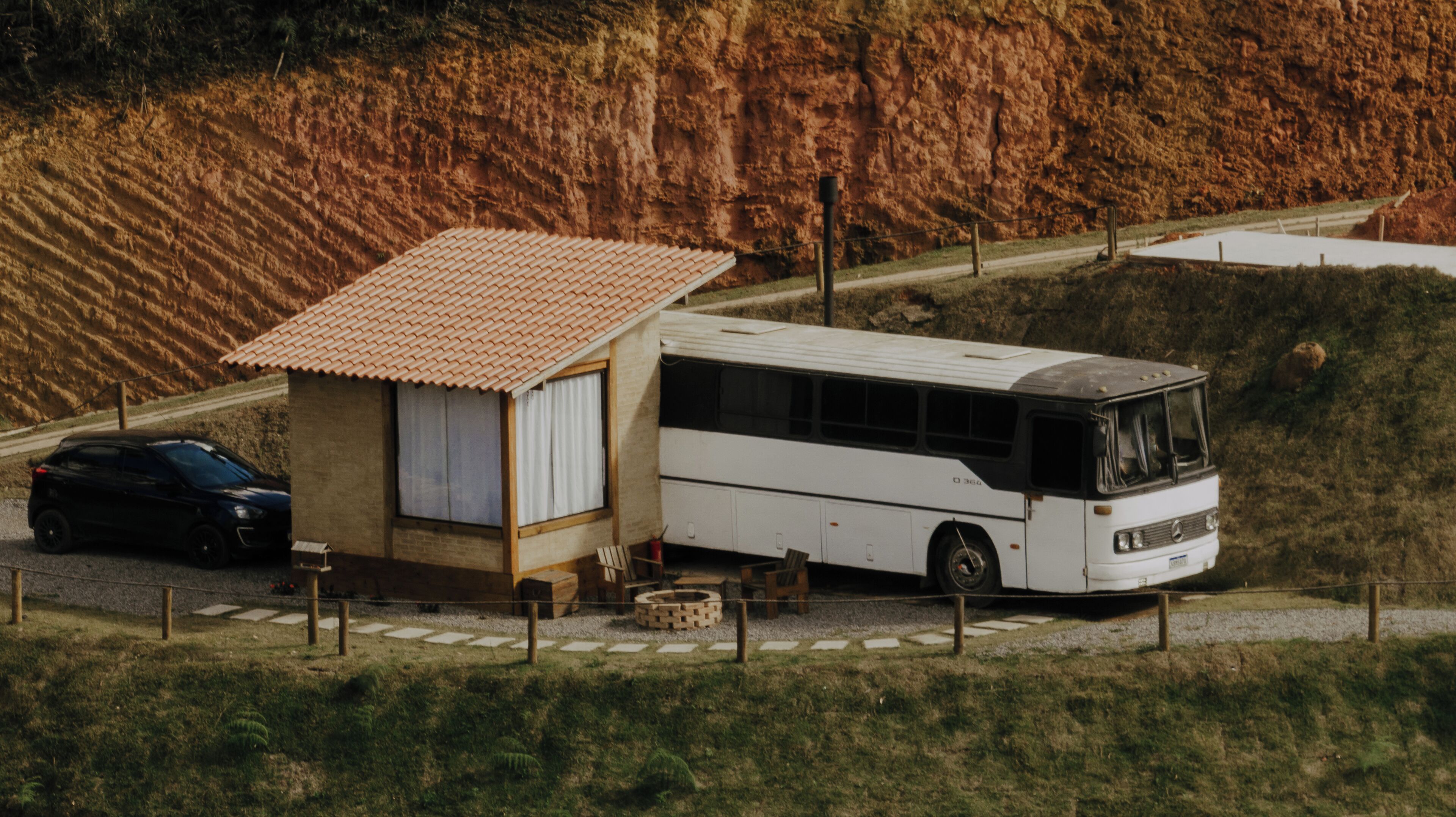 Ein kleines Haus mit einem Ziegeldach und einem weißen Bus davor.