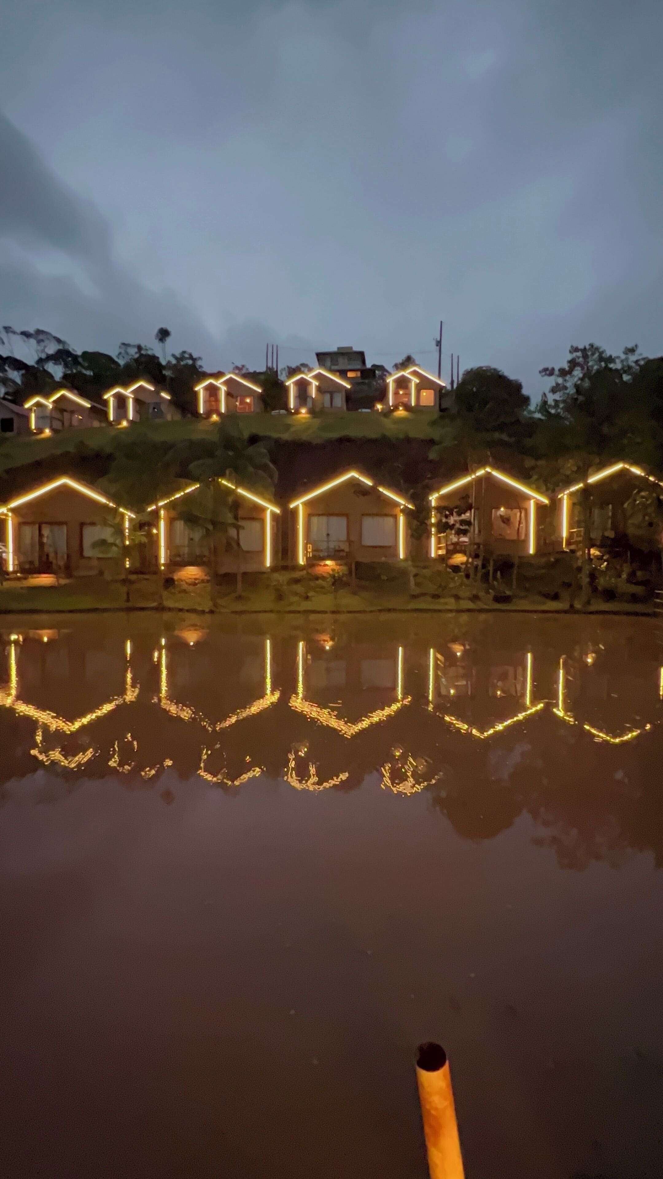 Una hilera de casas con contornos iluminados reflejados en el agua.