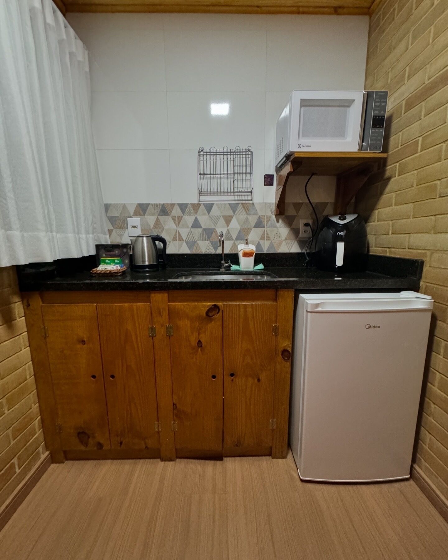 Eine kompakte Küche mit Mikrowelle, Wasserkocher und kleinem Kühlschrank.