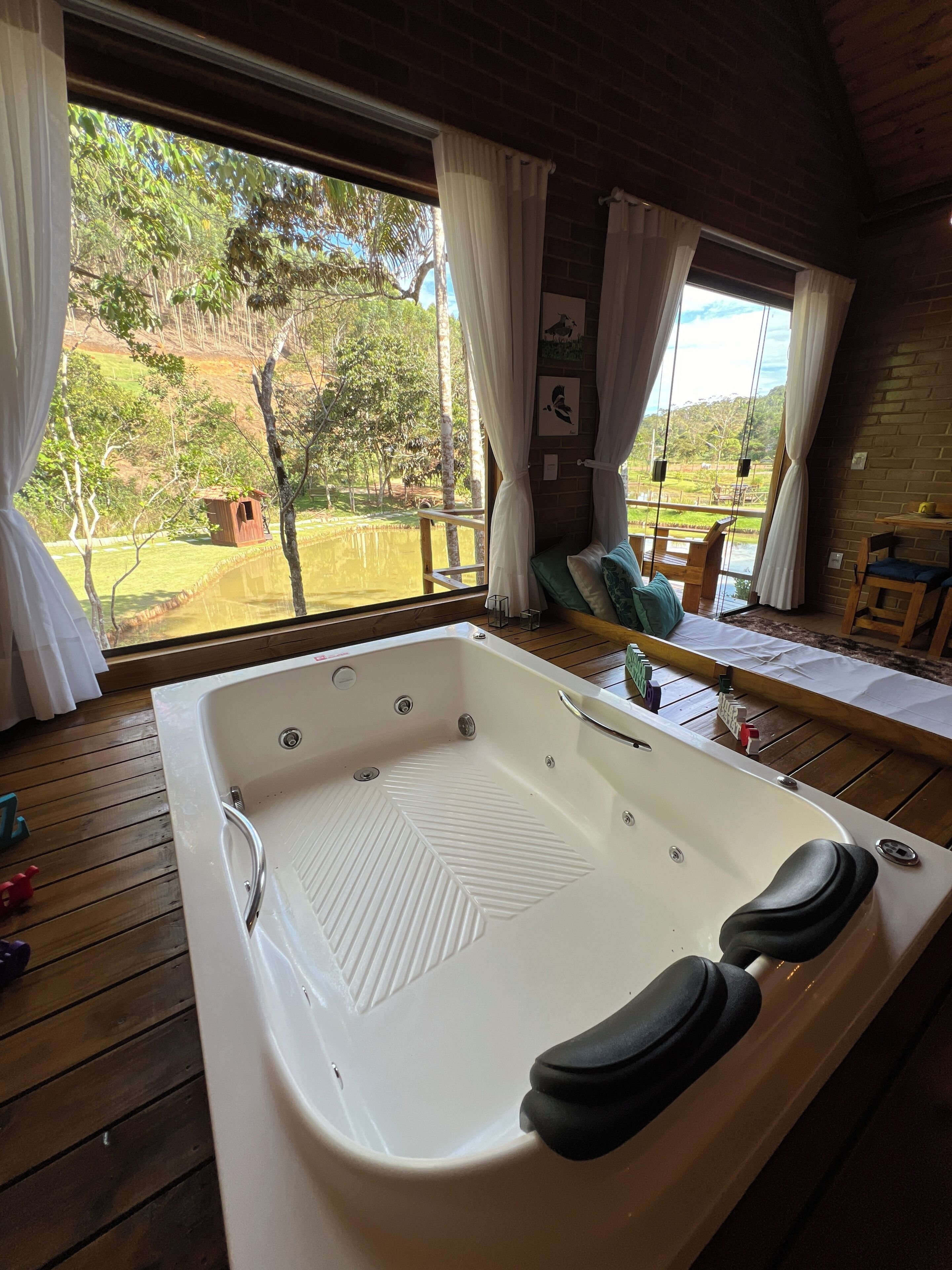 Une terrasse en bois avec une grande baignoire blanche, des meubles en bois et une vue sur un paysage naturel.