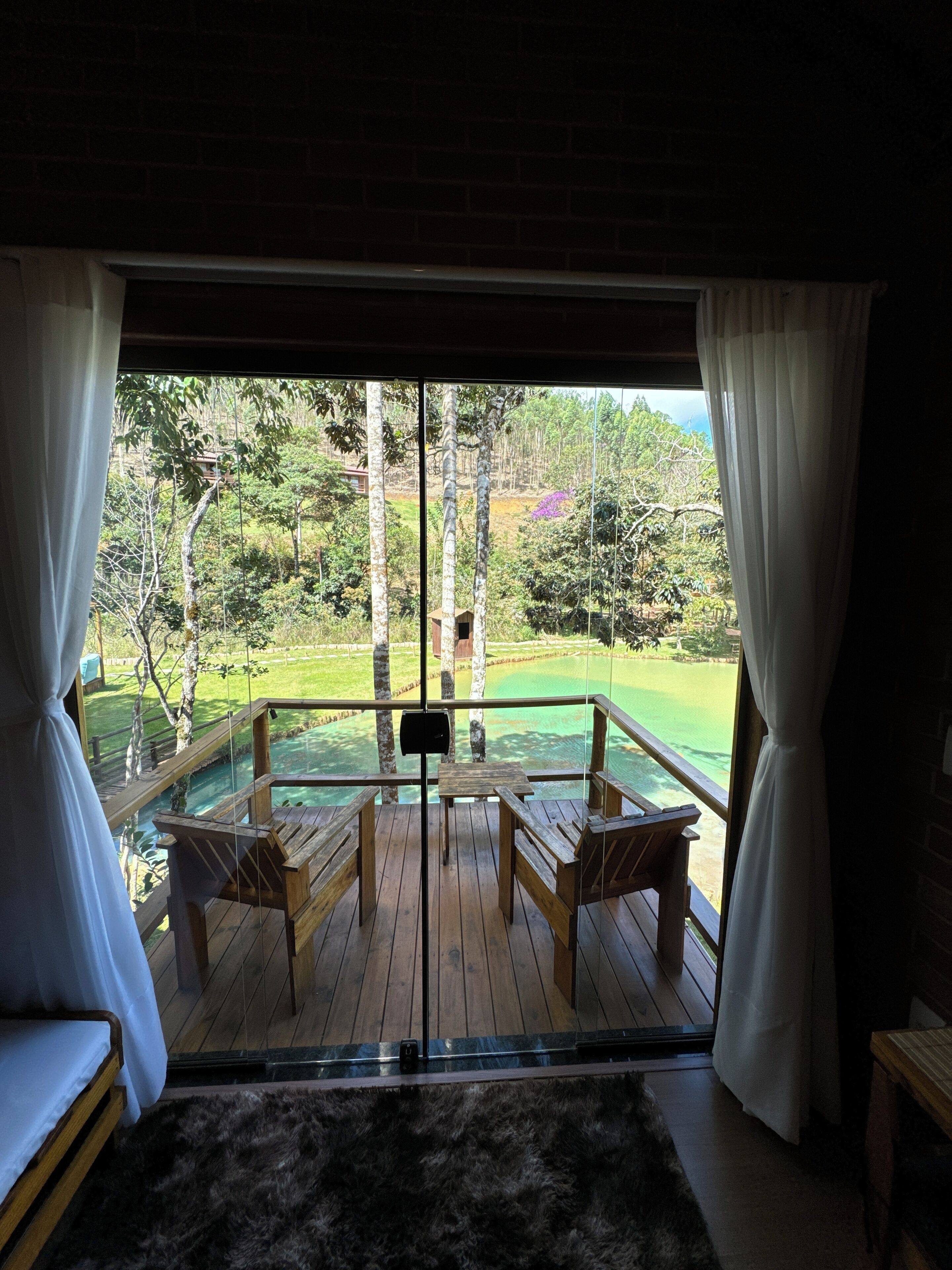 Una habitación con terraza de madera, puerta de vidrio y vista a un campo de golf.