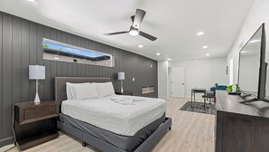 Une chambre moderne avec un lit, des tables de chevet, un bureau et un ventilateur de plafond.