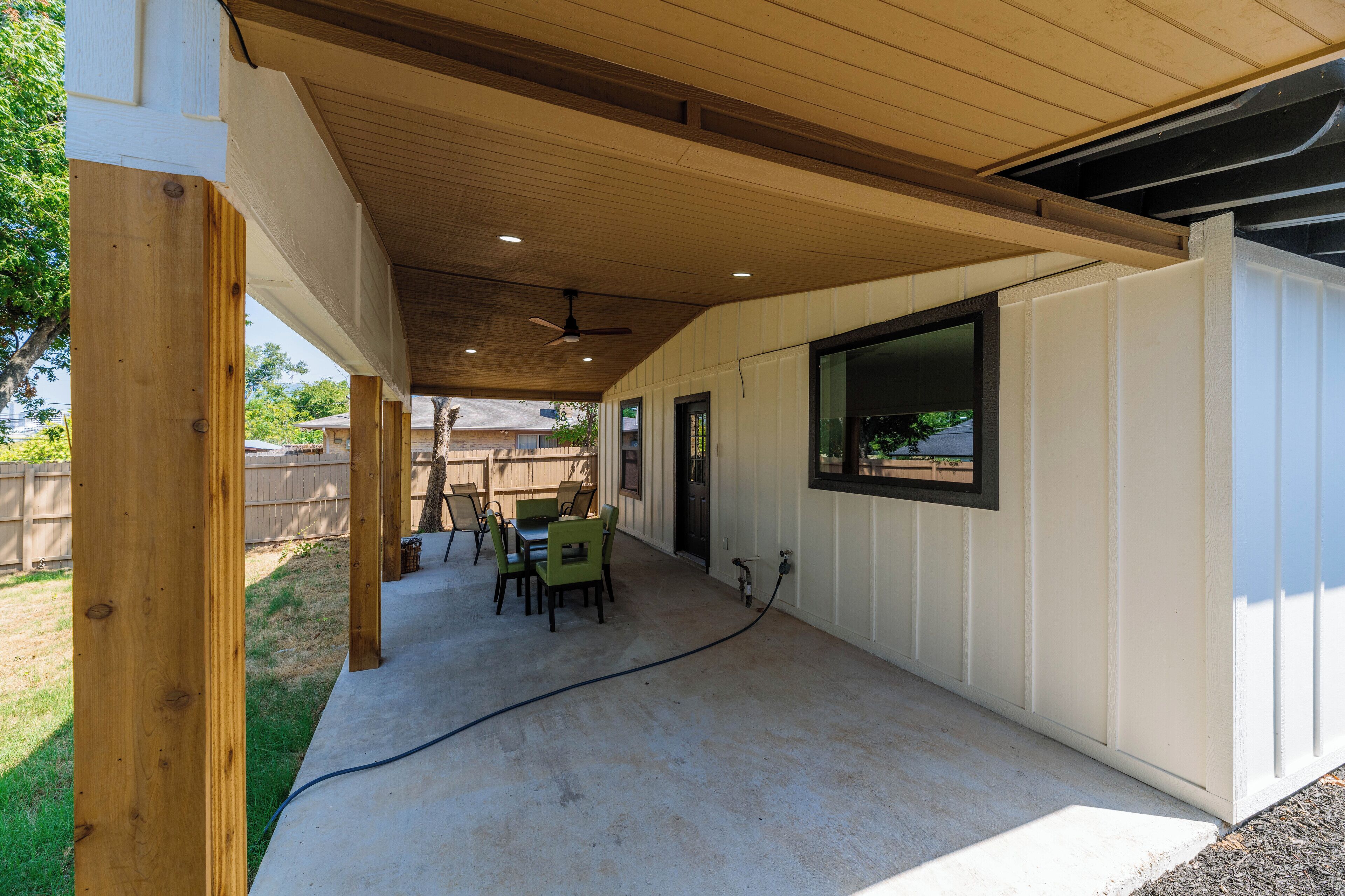 Ein überdachter Patio-Bereich mit Betonboden, Holzbalken und Deckenventilator.