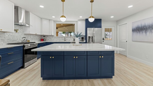 Une cuisine moderne dotée d’un îlot central, d’appareils électroménagers en acier inoxydable et de meubles de couleur bleue.