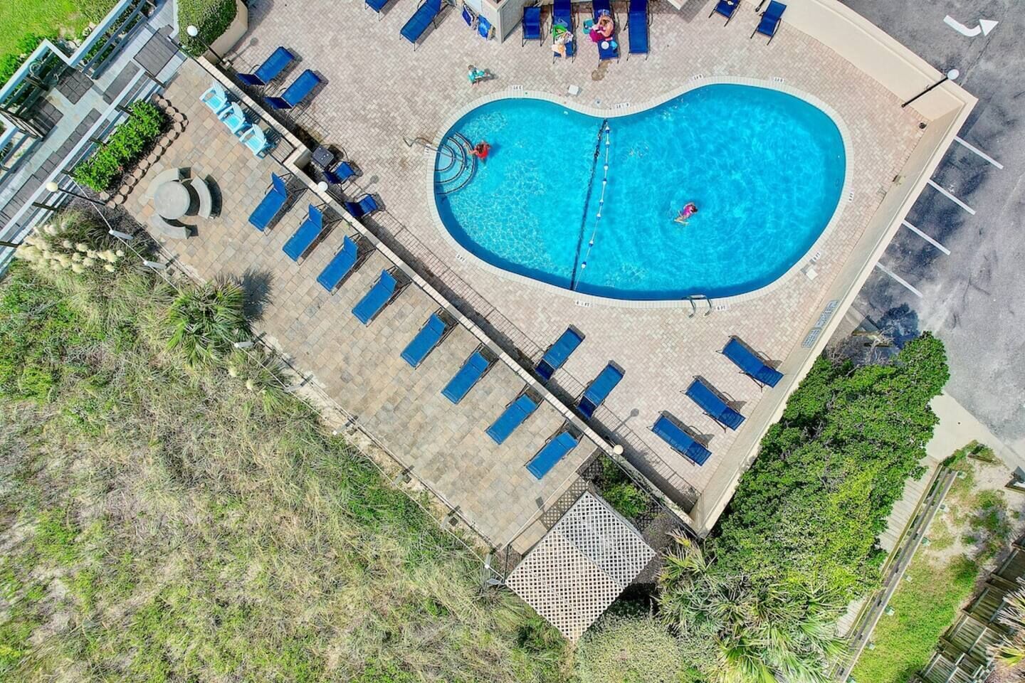 Ein Luftbild eines Schwimmbeckens mit Liegestühlen und einer kleinen Sonnenterrasse.