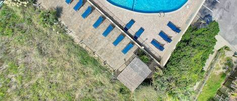 An aerial view of a swimming pool with sun loungers and a small deck area.