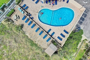 An aerial view of a swimming pool with sun loungers and a small deck area.