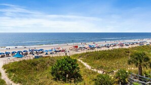 A beach with umbrellas, a lifeguard tower, and a clear sky.