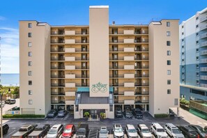 A multi-story hotel with a central entrance, parking lot, and balconies on each floor. - 4 Bds- Beachfront Balcony- near Barefoot- Pool (North Myrtle Beach)