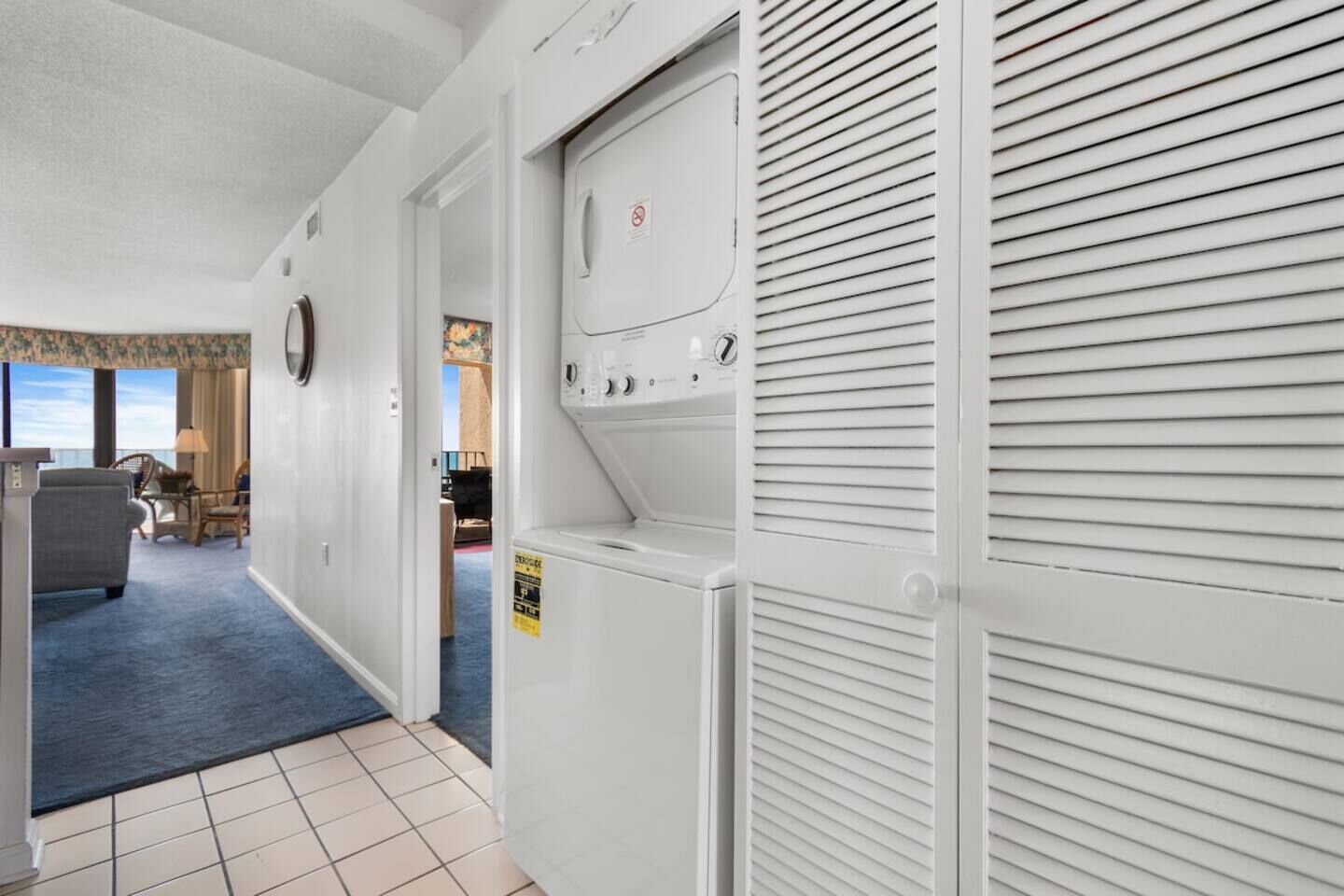 A hotel corridor with a seating area, a view of the sea, and a laundry room.