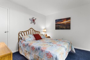 Un dormitorio con cama, mesita de noche, lámpara de pared, un adorno en la pared y un cuadro.