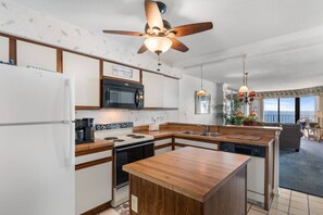 A modern kitchen with a central island, a microwave, a stove, and a ceiling fan.
