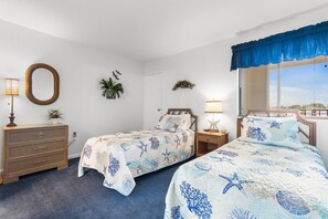 Un dormitorio con dos camas, un aparador, un espejo y una ventana con persianas.