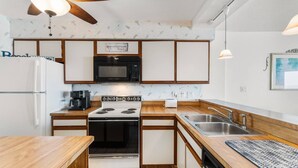 A compact kitchen with a stove, microwave, and sink.