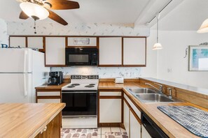 A compact kitchen with a stove, microwave, and sink.