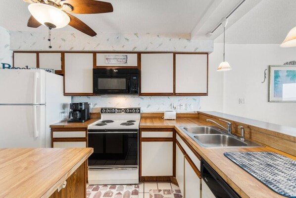 A compact kitchen with a stove, microwave, and sink.