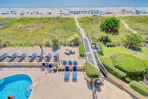 Um resort com área de piscina, espreguiçadeiras e vista para a praia.