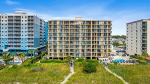 A multi-story hotel with balconies, a swimming pool, and a landscaped area.