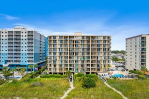 A multi-story hotel with balconies, a swimming pool, and a landscaped area.