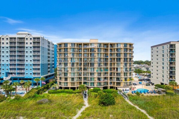 A multi-story hotel with balconies, a swimming pool, and a landscaped area.