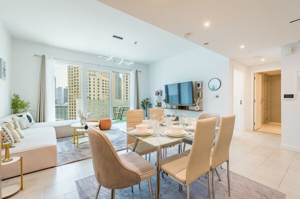 A modern apartment with a dining area, sofa, and a large window with a city view.