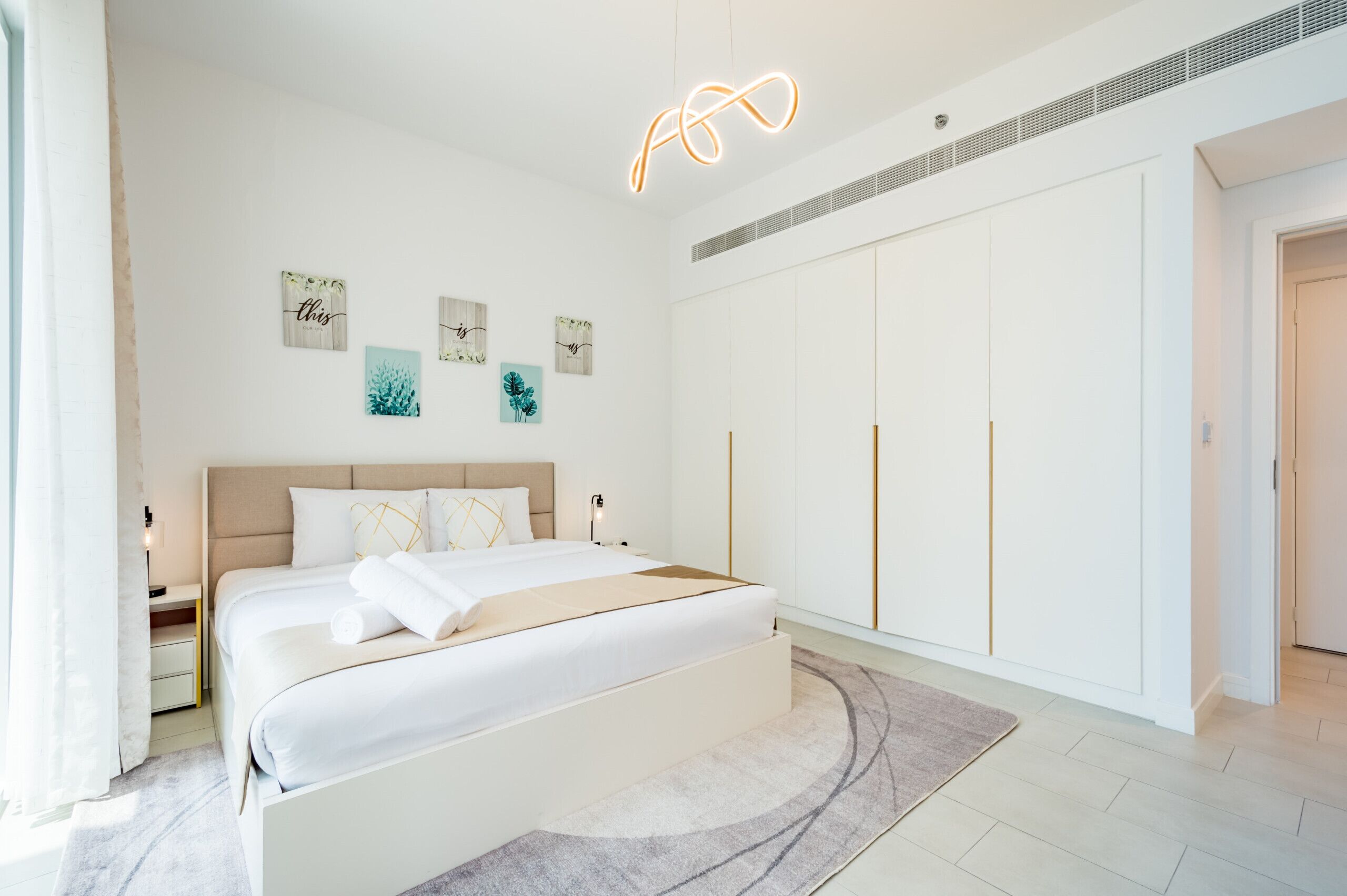 A modern bedroom with a large bed, a wardrobe, and wall art.