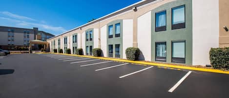 Un hotel con varias habitaciones, un estacionamiento y un cielo azul despejado.
