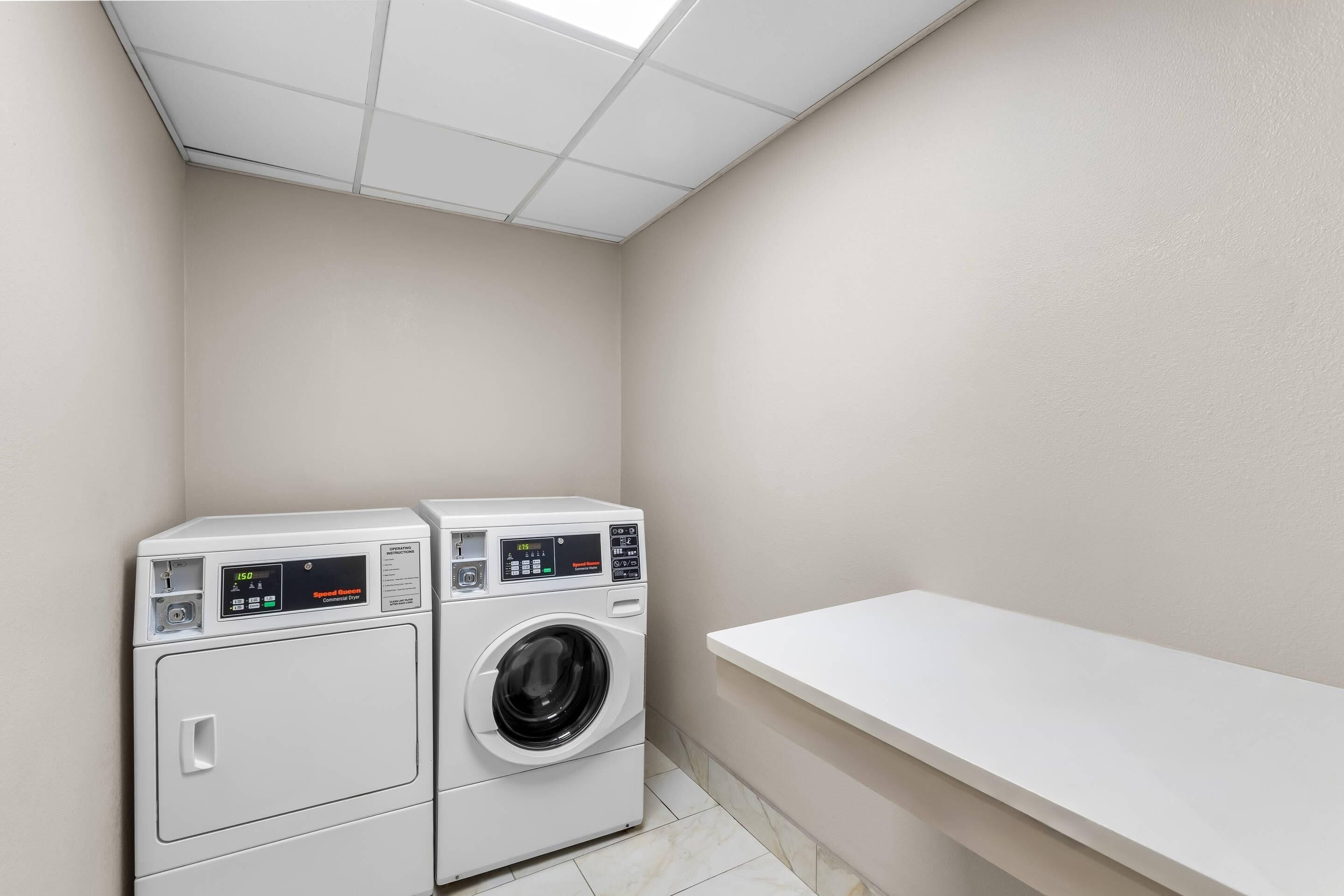 A laundry room with two washing machines and a white shelf.