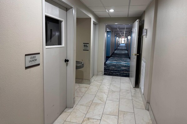 A hotel hallway with a guest laundry sign, a handwashing station, and a tiled floor. - Quality Inn Chattanooga Hamilton Place (Chattanooga)