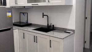 A modern kitchen with white cabinets, a stainless steel refrigerator, a black sink, and a microwave. - New Furn 1 Br/1 Bath/Kitchen, Manila-Univ Belt, AC, Hot water, Wifi, Netflix -u1 (Manila)