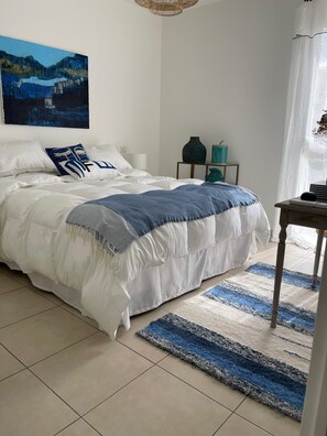 Cozy retreat with a large bed, nightstand, and decorative table, set against a serene landscape painting.