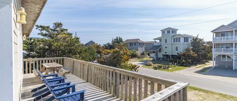 A wooden deck with blue lounge chairs, a picnic table, and a view of neighboring houses.