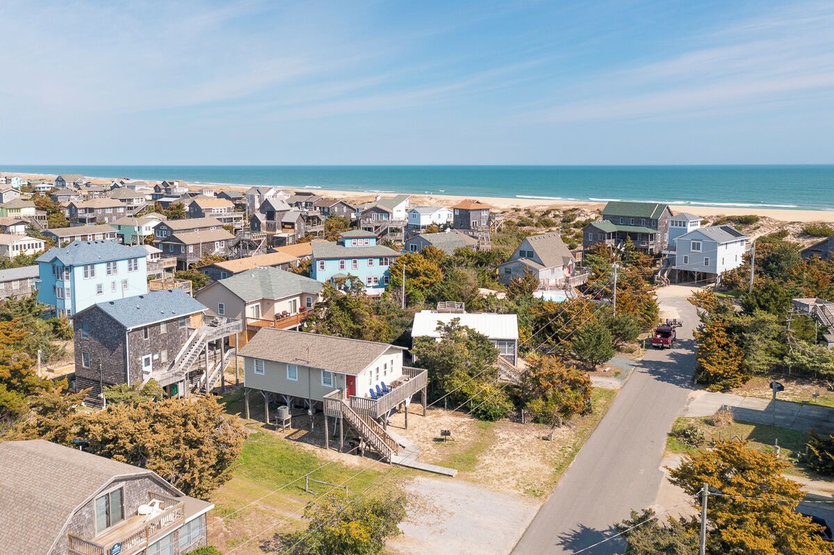 A coastal residential area with houses, a beach, and a road.