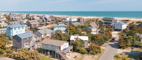 A coastal residential area with houses, a beach, and a road.