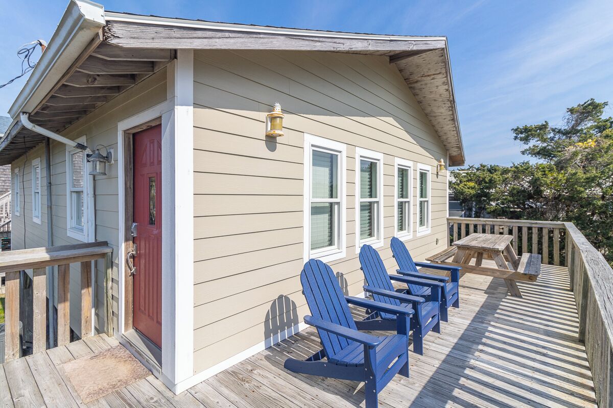 A wooden deck with blue Adirondack chairs and a picnic table.