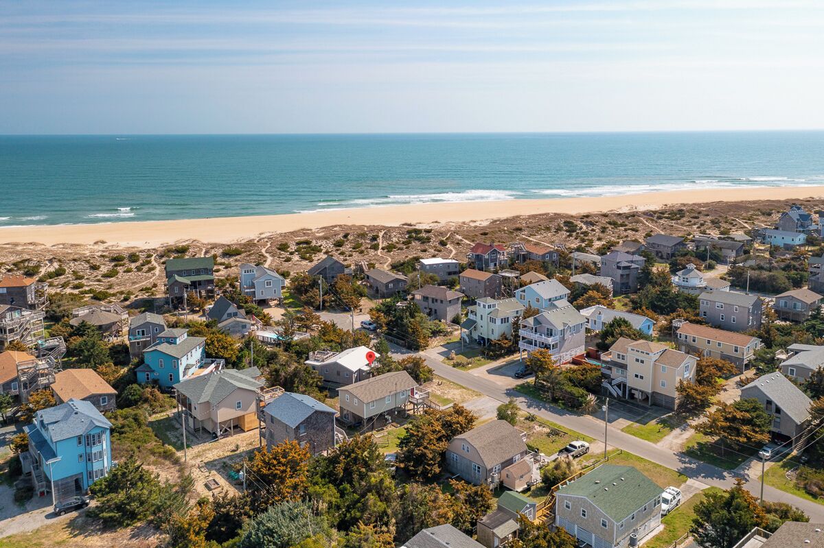 A coastal residential area with houses, a beach, and a clear view of the ocean.